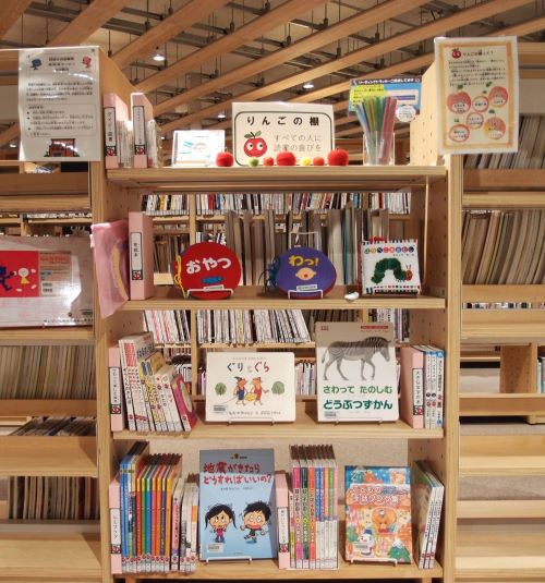 棚に本が並んでいる写真。中央上段の棚にりんごの棚の紹介のパネルが設置されている
