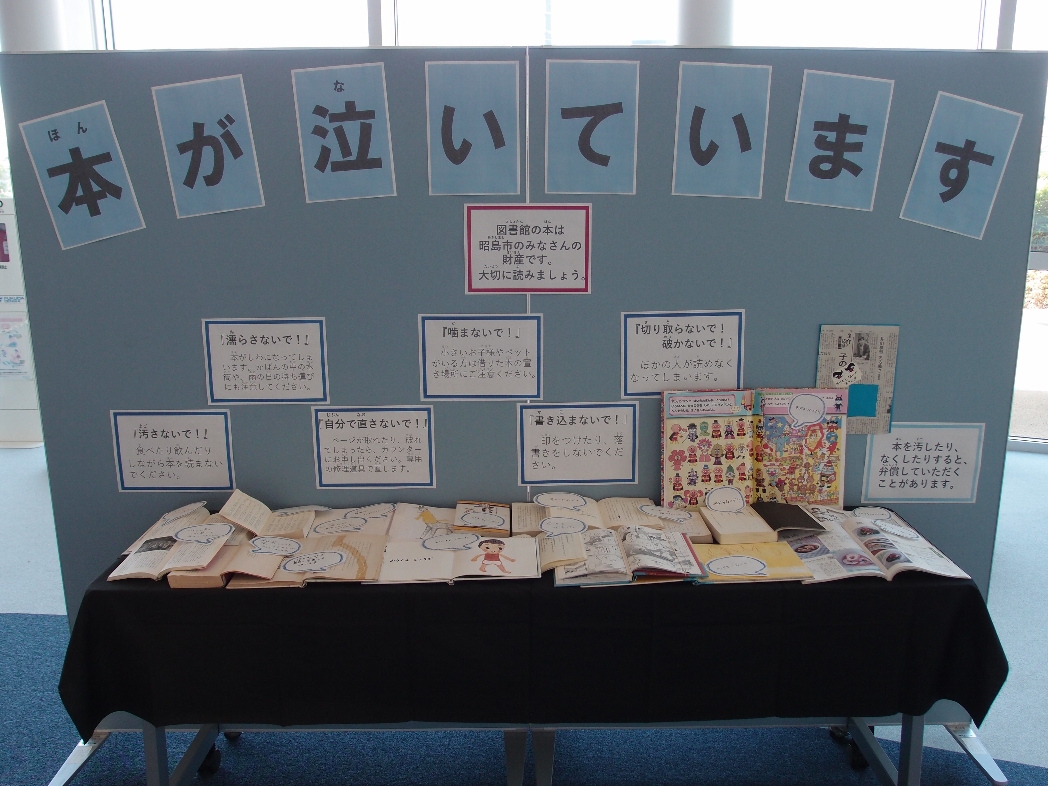 本が泣いていますという大きな文字と、その下に汚れたり破れたり濡れてしまった本達が開いた状態で展示されている。