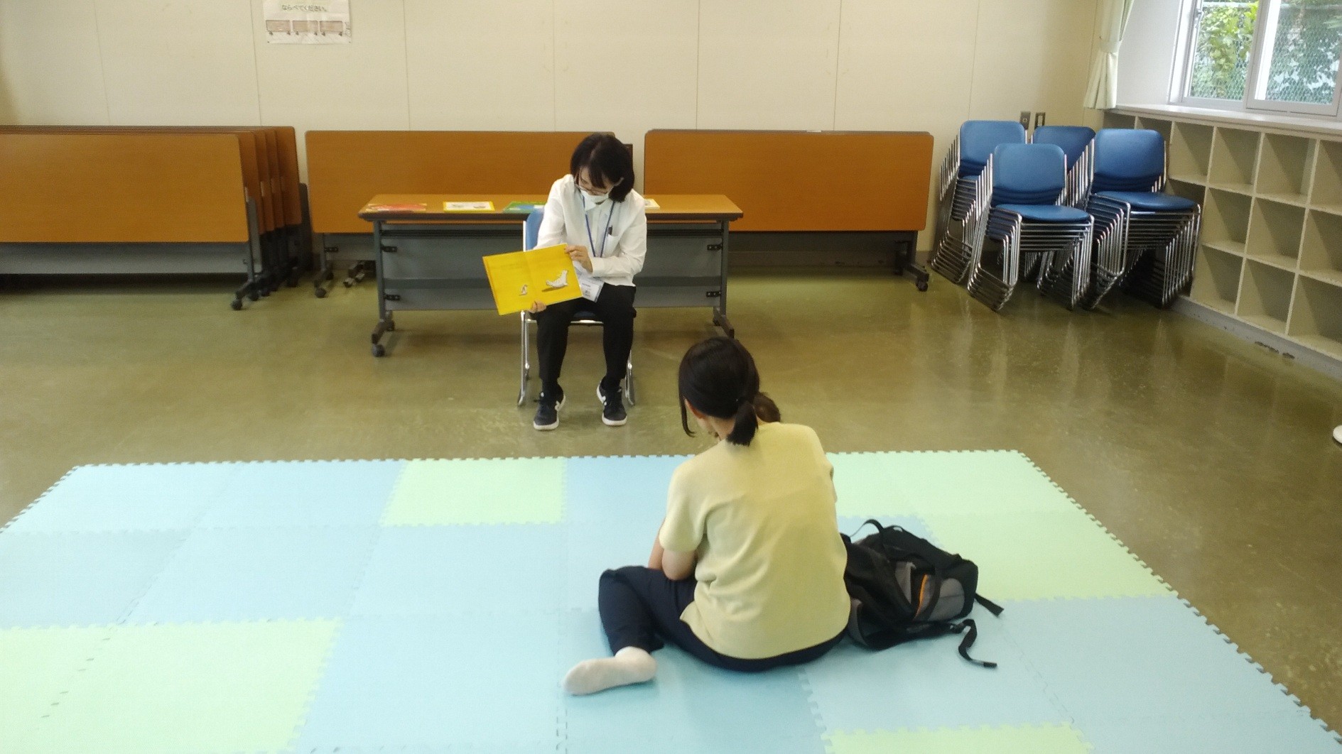 女性がお子さんに向けて絵本を読み聞かせしている様子の写真