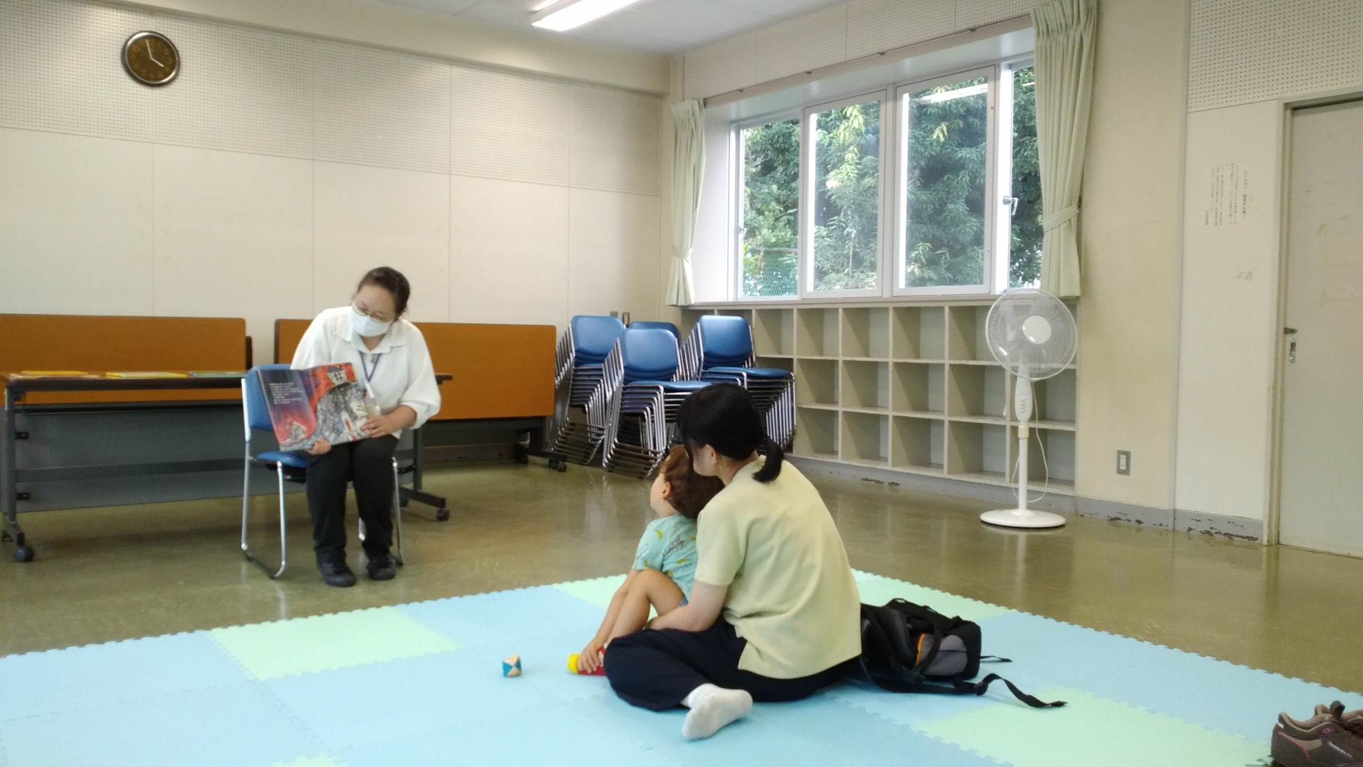 女性がお子さんに向けて絵本を読み聞かせしている様子の写真